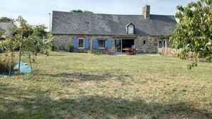 A stone house with a sloped roof, a chimney, and a small attached garage. - Single-storey house 100 m from the strikes (Courtils)