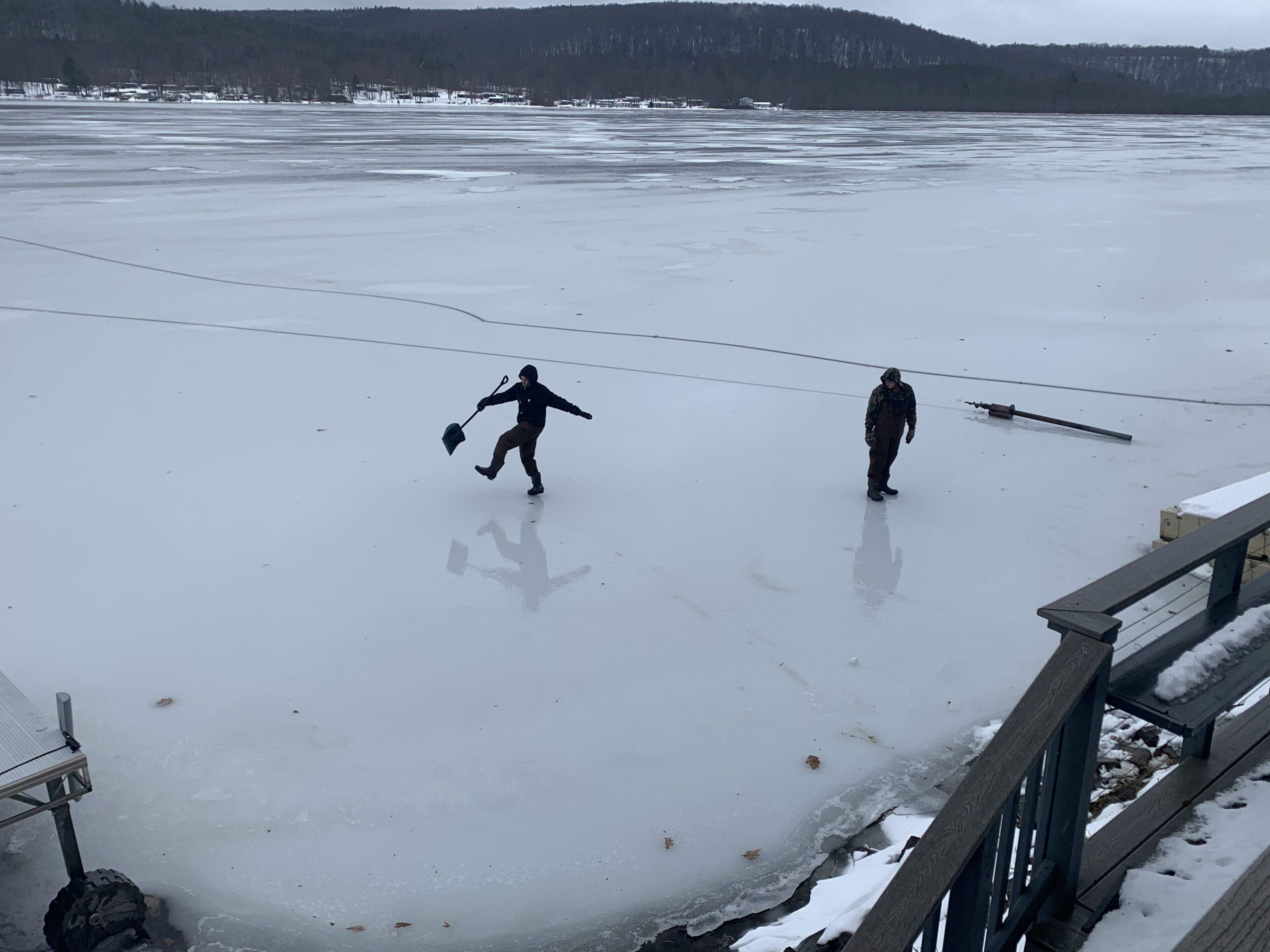 A frozen lake with a wooden dock and a metal railing.