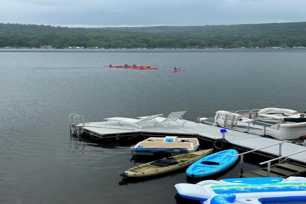 Un quai où sont amarrés plusieurs bateaux, dont des kayaks et un petit canot, ainsi qu’une plateforme flottante sur l’eau.
