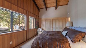 Une chambre avec un grand lit, des murs en bois, une fenêtre et une porte.