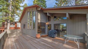 Une terrasse en bois avec un barbecue et une table en verre.