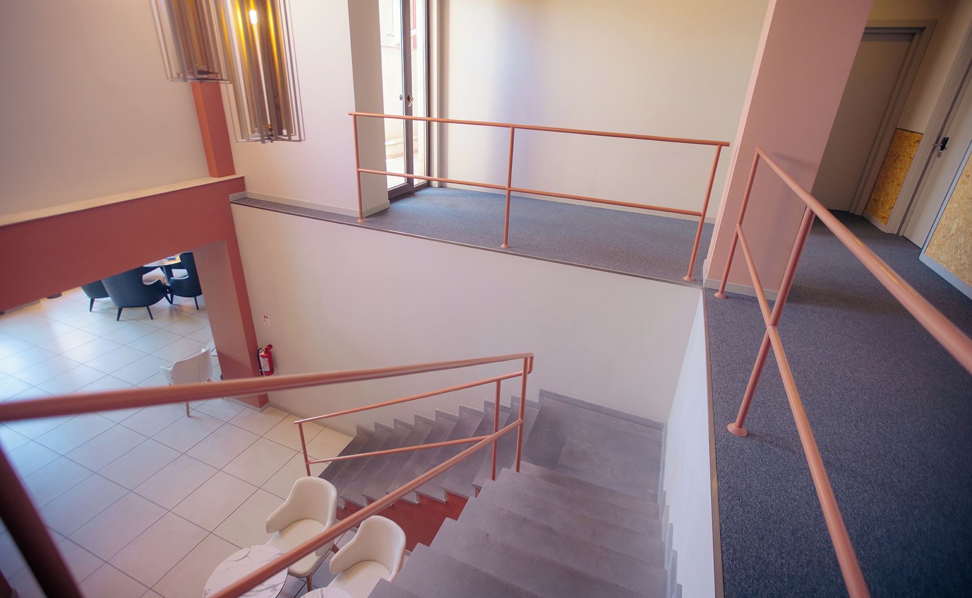 A multi-level interior with a staircase, a fire extinguisher, and a seating area.