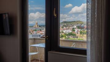 A room with a sliding glass door leading to an outdoor balcony with a view of a cityscape.