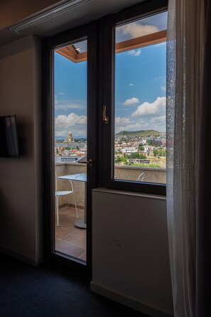A room with a sliding glass door leading to an outdoor balcony with a view of a cityscape. - KING TAMAR HOTEL By LUXURIA HOTELS (Tbilisi)