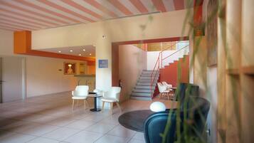 Een hotel lobby met een trap, zithoek en een receptiebalie.