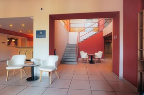 Un hall de hotel con una recepción, zona de estar y una escalera.