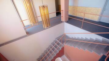A multi-level interior with a staircase, metal railings, and a fire extinguisher.