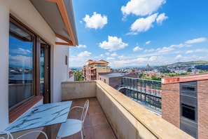 A balcony with a view of a cityscape, a table, and two chairs. - KING TAMAR HOTEL By LUXURIA HOTELS (Tbilisi)