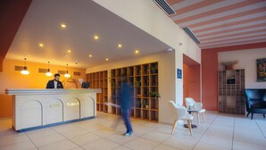Een hotel receptie met een balie, zitplaatsen en een groot kastenmeubel.