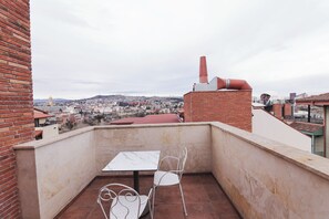 A balcony with a table and chairs, overlooking a cityscape with buildings and a dome structure. - KING TAMAR HOTEL By LUXURIA HOTELS (Tbilisi)