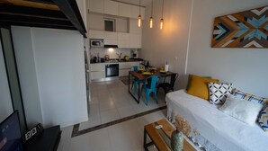 A modern kitchen with white cabinets, a dining table with blue chairs, and pendant lights. - Hotel comfort in a prestigious residence (Chéraga)
