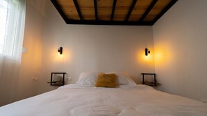 A bedroom with a wooden ceiling, two wall-mounted light fixtures, a bed with white bedding, and a single brown pillow. - Hotel comfort in a prestigious residence (Chéraga)