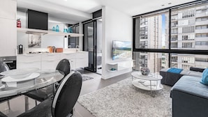 Eine moderne Wohnung mit Essbereich, Küche, Wohnzimmer und großen Fenstern mit Blick auf die Stadt.