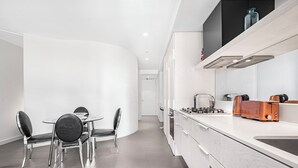 Eine moderne Küche mit Gasherd, Toaster und Mikrowelle. Es gibt einen Essbereich mit Tisch und Stühlen.
