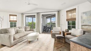 Ein geräumiges Wohnzimmer mit einer großen Couch, einem Couchtisch und einem Essbereich mit Stühlen.