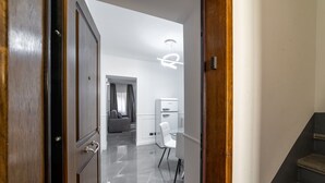 A modern interior with a wooden door, a staircase, a kitchen area, and a seating area with a sofa and chairs. - iRoome Rome (Roma)