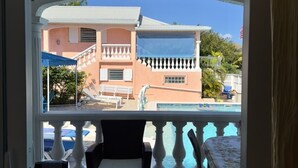 A balcony with a view of a building, a pool, and outdoor furniture. - Detached yellow studio in front of the pool 150m from the beach! (saint martin)