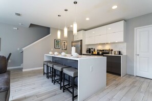 A modern kitchen with a central island, bar stools, and pendant lighting.
