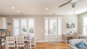 A spacious living area with a dining table, chairs, a sofa, and a ceiling fan.