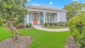 A single-story house with a red front door, a covered porch, and a well-maintained lawn.