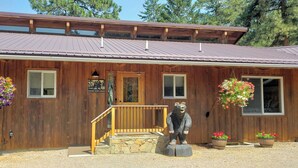 A wooden lodge with a metal roof, a front porch, and a bear statue.