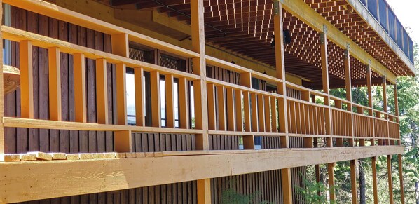 A wooden balcony with vertical railings and a wooden floor. - Luxury Lodge: Flathead Lake & Wild Horse Island (Big Arm)