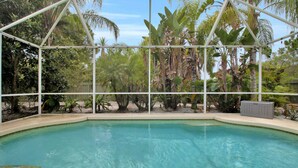 A clear pool with a glass enclosure, surrounded by tropical plants and trees. - Stylish & Bright, Mins to Downtown, Pool, Parking (North Port)