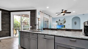 A modern kitchen with grey cabinets, a dishwasher, and a large island. - Stylish & Bright, Mins to Downtown, Pool, Parking (North Port)
