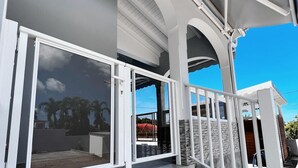 A modern outdoor staircase leading to a covered area with glass doors, stone walls, and a clear view of the sky.