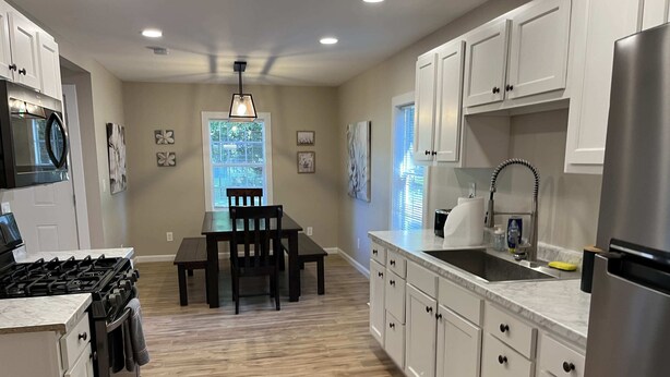 A modern kitchen with white cabinets, a dining table with chairs, a built-in oven, and a stainless steel refrigerator. - Wilson, Two Bedroom House in Historic Loveland (Loveland)