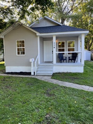 A single-story house with a front porch, a mailbox, and a small outdoor seating area with two chairs. - Wilson, Two Bedroom House in Historic Loveland (Loveland)