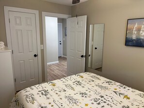A bedroom with a bed, a mirror, and two doors leading to other rooms. - Wilson, Two Bedroom House in Historic Loveland (Loveland)