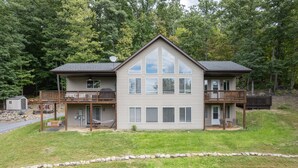 Ein zweistöckiges Haus mit einem Balkon im ersten Stock und einer Terrasse im zweiten Stock.