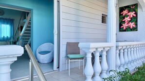 A porch with white balustrades, a wicker chair, and a green cushion. - Studio Indépendant Devant Piscine et BBQ à Orient Bay à 5 Minutes de la Plage ! (saint martin)