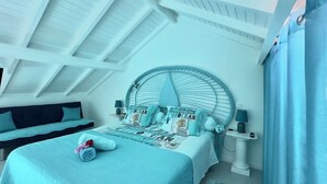 A bedroom with a bed, a round headboard, a bedside table, and a nightstand. - Studio Indépendant Devant Piscine et BBQ à Orient Bay à 5 Minutes de la Plage ! (saint martin)