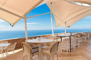 Zona salotto all'aperto con tavoli e sedie, con vista sul mare.