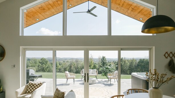 Une pièce spacieuse dotée d’une grande fenêtre, d’un ventilateur de plafond et offrant une vue sur un patio extérieur.