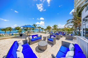 A beachside lounge with outdoor seating, a view of the ocean, and palm trees. - Gorgeous Sunny Isles Beach Condo w/Balcony an Ocean View & Direct Beach Access! (Sunny Isles Beach)
