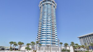 Un grand hôtel cylindrique à la façade bleue et blanche, entouré de palmiers et surplombant un ciel dégagé.
