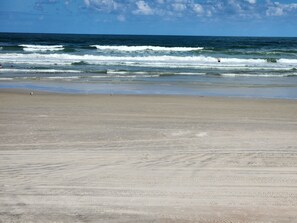 Ein Strand mit Wellen, sandigem Ufer und blauem Himmel.