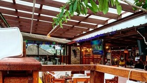 An outdoor seating area with wooden furniture and a covered section with a view of the street.