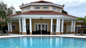 A swimming pool with a hot tub area, surrounded by lounge chairs and a building with a tiled roof. - Gated, NO stairs, NO carpet 1 min walk to lakefront POOL, PICKLEBALL/TENNIS (Sarasota)