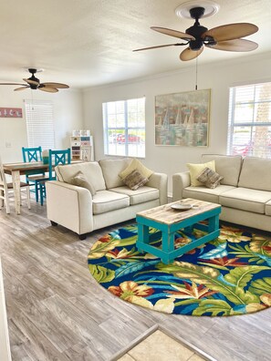 A living room with two white sofas, a coffee table, a ceiling fan, and a colorful rug. - Gated NO stairs, NO carpet 1 min walk to lakefront POOL & PICKLEBALL (Sarasota)