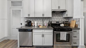 A modern kitchen with white cabinetry, stainless steel appliances, and a patterned backsplash. -  New/Midtown Sac/Free Parking/Coffee/Long stays welcomed (Sacramento)
