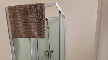 Een badkamer met een douche met glazen wand, een toilet en een wastafel met kast.