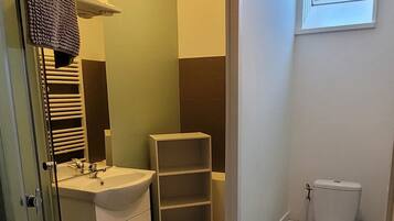 Een moderne badkamer met een douchecabine van glas, een wit wastafelmeubel, een toilet en een inbouwkastenwand.