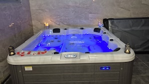 A hot tub with blue LED lights, a control panel, and decorative candles.