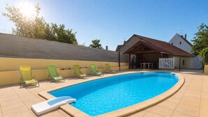 A swimming pool with a diving board, surrounded by lounge chairs, and a covered patio area.