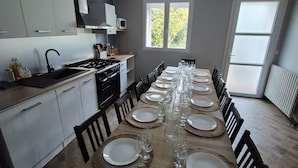 A modern kitchen with white cabinets, a built-in microwave, and a dining area set for six with a long wooden table.