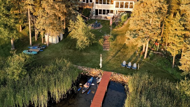 Ein zweistöckiges Haus mit einer großen Terrasse und einem Steg, der in einen Teich führt.